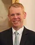 A smiling man wearing a dark business suit and tie